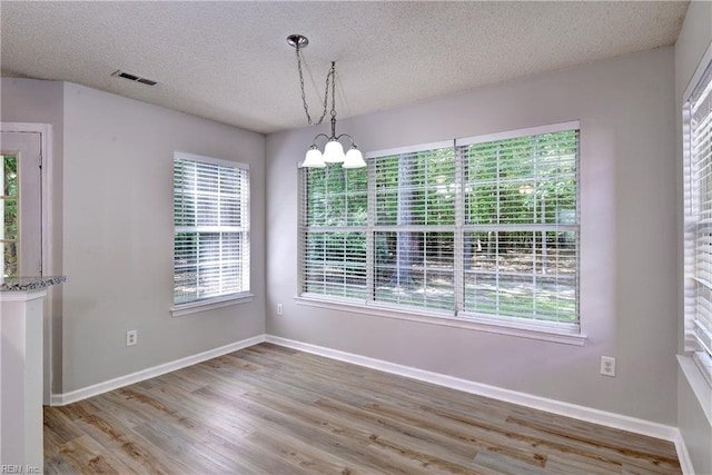 3957 Driftwood Way, Williamsburg, VA 23188 - unfurnished dining area featuring plenty of natural light, a chandelier, a textured ceiling, and wood finished floors