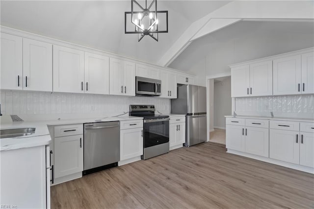 1320 Clay St, Franklin, VA 23851 - kitchen featuring appliances with stainless steel finishes, decorative backsplash, light wood-type flooring, and lofted ceiling