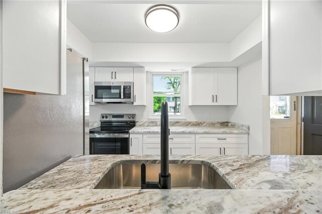 1409 Amberley Forest Rd, Virginia Beach, VA 23453 - kitchen with stainless steel appliances, light stone counters, and white cabinets