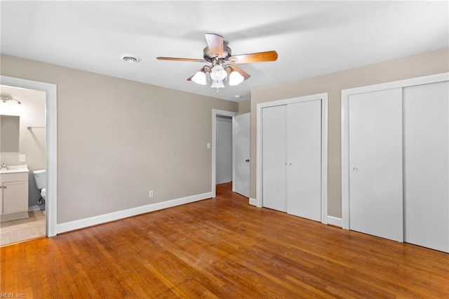 416 N Broad St, Suffolk, VA 23434 - unfurnished bedroom featuring multiple closets, light wood-style floors, ensuite bath, and a ceiling fan
