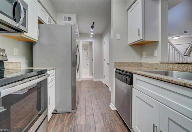 3856 Lasalle Dr Unit 107, Virginia Beach, VA 23453 - kitchen featuring appliances with stainless steel finishes, dark wood-style floors, white cabinetry, a textured ceiling, and light stone counters