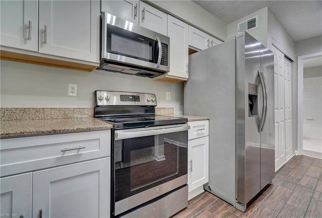 3856 Lasalle Dr Unit 107, Virginia Beach, VA 23453 - kitchen featuring appliances with stainless steel finishes, dark wood-type flooring, light stone counters, and white cabinets