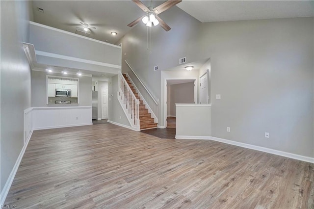 3856 Lasalle Dr Unit 107, Virginia Beach, VA 23453 - unfurnished living room with ceiling fan, stairs, light wood-style flooring, and high vaulted ceiling