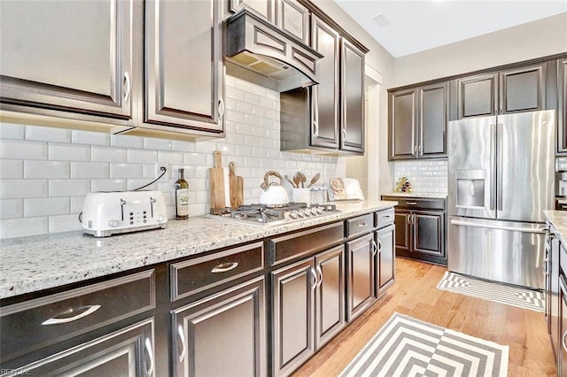 113 Saint Andrews, Smithfield, VA 23430 - kitchen with appliances with stainless steel finishes, premium range hood, dark brown cabinets, light wood-type flooring, and light stone countertops