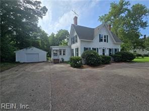 1697 Old Ferry Rd, Hudgins, VA 23076 - view of home's exterior with a detached garage, an outdoor structure, a chimney, and asphalt driveway