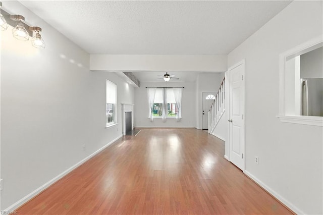 182 Old Bridge Rd, Newport News, VA 23608 - unfurnished living room with wood finished floors, stairs, ceiling fan, a textured ceiling, and a fireplace