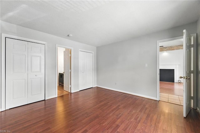 182 Old Bridge Rd, Newport News, VA 23608 - unfurnished bedroom with wood finished floors, a fireplace, and multiple closets