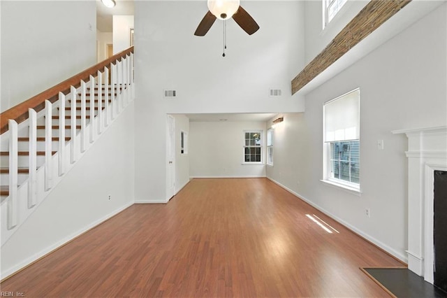 182 Old Bridge Rd, Newport News, VA 23608 - unfurnished living room featuring a towering ceiling, stairway, a ceiling fan, wood finished floors, and a fireplace with raised hearth