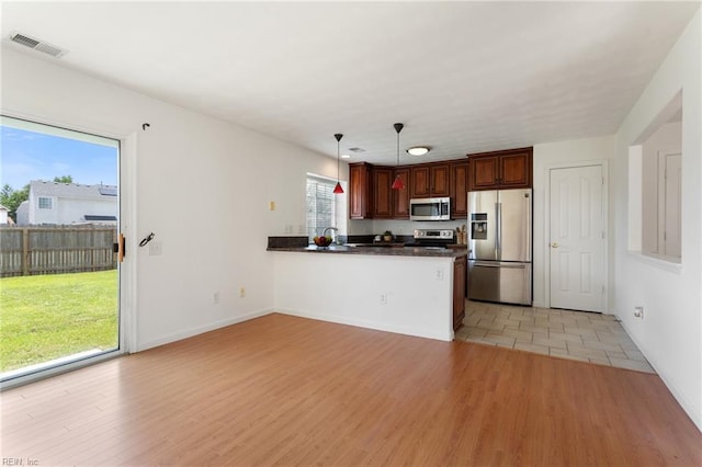 5405 Kiawah Ct, Virginia Beach, VA 23462 - kitchen with appliances with stainless steel finishes, dark countertops, a peninsula, decorative light fixtures, and light wood-style flooring