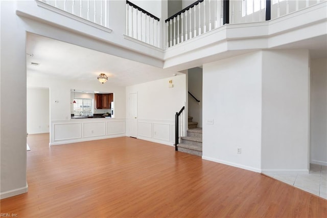 5405 Kiawah Ct, Virginia Beach, VA 23462 - unfurnished living room featuring light wood finished floors, stairway, and a towering ceiling