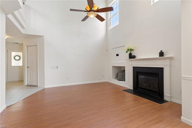 5405 Kiawah Ct, Virginia Beach, VA 23462 - unfurnished living room featuring a towering ceiling, a fireplace with flush hearth, healthy amount of natural light, a ceiling fan, and light wood-style floors