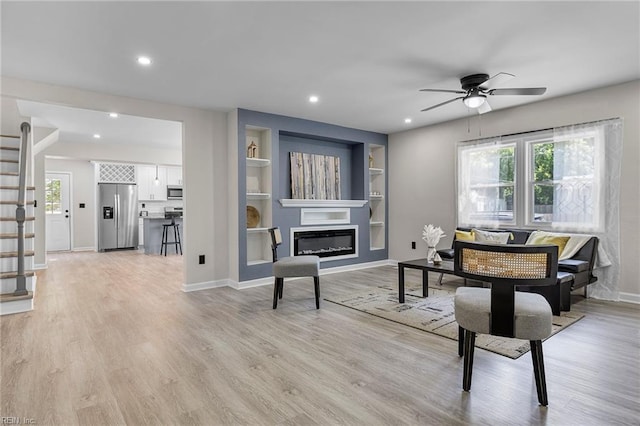 21 Rodgers Pl, Portsmouth, VA 23702 - living room with stairs, a ceiling fan, light wood-style floors, a glass covered fireplace, and built in shelves