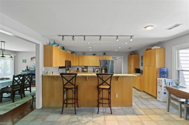 1292 Holly Point Rd, Virginia Beach, VA 23454 - kitchen featuring stainless steel fridge, a peninsula, rail lighting, light countertops, and a breakfast bar area