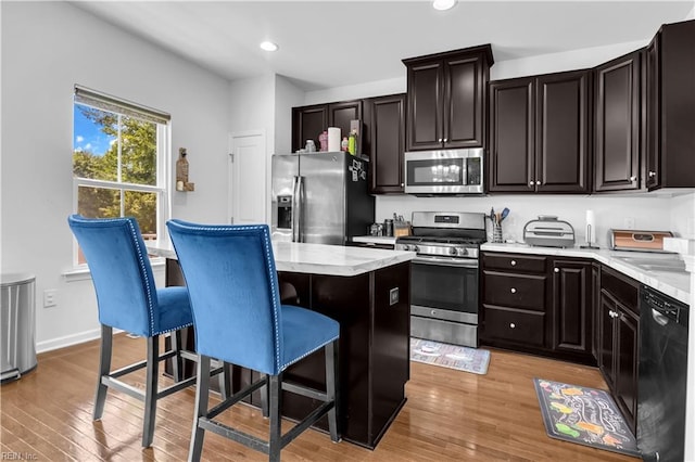 600 Grimes Way, Chesapeake, VA 23324 - kitchen featuring appliances with stainless steel finishes, a kitchen breakfast bar, light countertops, a kitchen island, and light wood-style flooring
