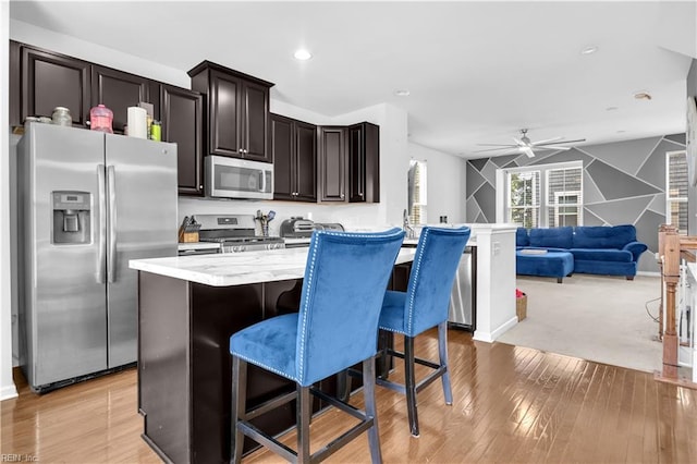 600 Grimes Way, Chesapeake, VA 23324 - kitchen with stainless steel appliances, ceiling fan, a kitchen bar, light wood-style floors, and open floor plan