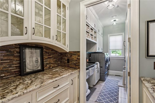 201 Glebe Spring Ln, Yorktown, VA 23693 - kitchen with washer and dryer, tasteful backsplash, light stone counters, glass insert cabinets, and light tile patterned floors