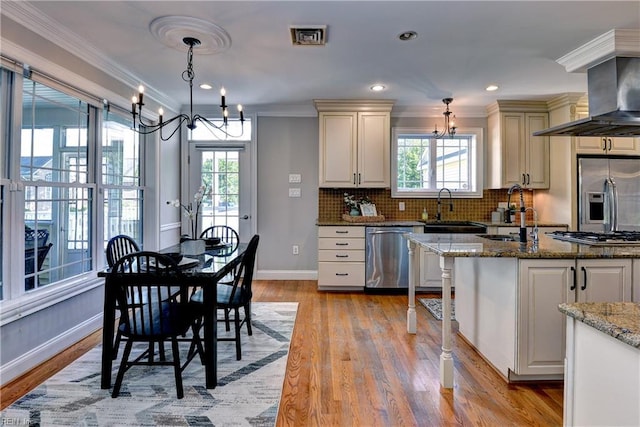 66 Heron Harbor Way, Hudgins, VA 23076 - kitchen with stainless steel appliances, a chandelier, healthy amount of natural light, wall chimney range hood, and ornamental molding