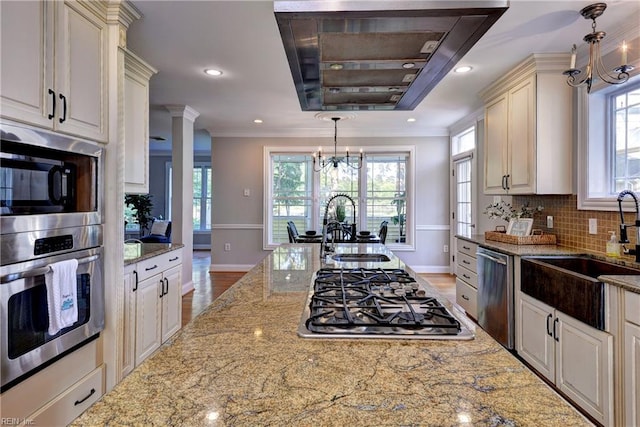 66 Heron Harbor Way, Hudgins, VA 23076 - kitchen with a chandelier, stainless steel appliances, range hood, light stone counters, and plenty of natural light