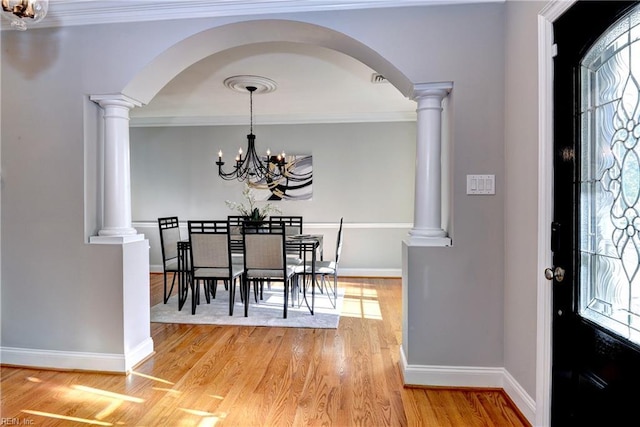 66 Heron Harbor Way, Hudgins, VA 23076 - dining space featuring a chandelier, arched walkways, light wood-style floors, decorative columns, and ornamental molding