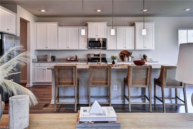 9116 Daydreamer Ct, Toano, VA 23168 - kitchen featuring stainless steel appliances, wood finished floors, recessed lighting, white cabinets, and light stone countertops