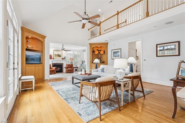 2841 Bennetts Pond Rd, Williamsburg, VA 23185 - living room with a ceiling fan, a high ceiling, light wood-style flooring, a lit fireplace, and built in features