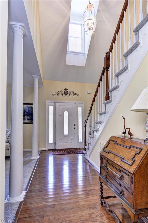 2712 Holly Ridge Ln, Williamsburg, VA 23185 - entrance foyer featuring decorative columns, a high ceiling, wood-type flooring, stairs, and a chandelier