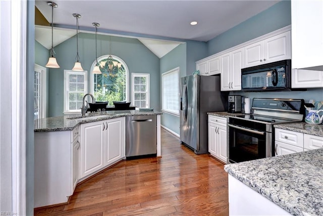 2712 Holly Ridge Ln, Williamsburg, VA 23185 - kitchen featuring stainless steel appliances, vaulted ceiling, white cabinetry, wood finished floors, and decorative light fixtures