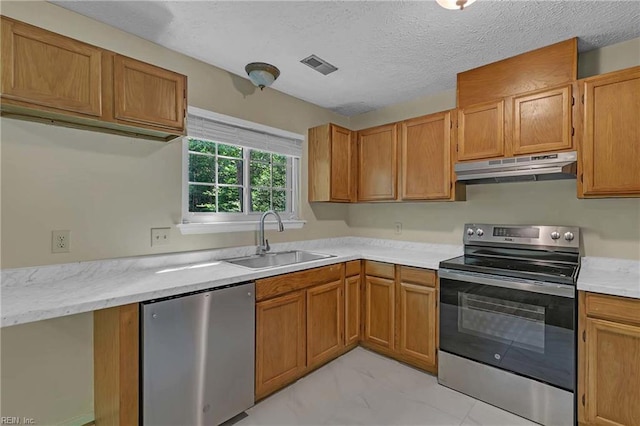 4505 Wimbledon Way, Williamsburg, VA 23188 - kitchen featuring appliances with stainless steel finishes, under cabinet range hood, light marble finish floors, brown cabinets, and a textured ceiling