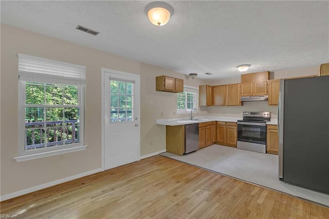 4505 Wimbledon Way, Williamsburg, VA 23188 - kitchen featuring stainless steel appliances, light countertops, a textured ceiling, light wood-style flooring, and under cabinet range hood