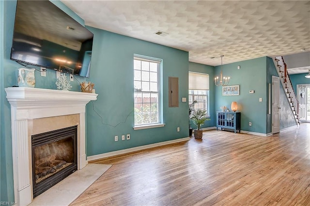 1212 Gunn Hall Dr, Virginia Beach, VA 23454 - unfurnished living room featuring a fireplace with flush hearth, wood finished floors, a chandelier, stairway, and electric panel