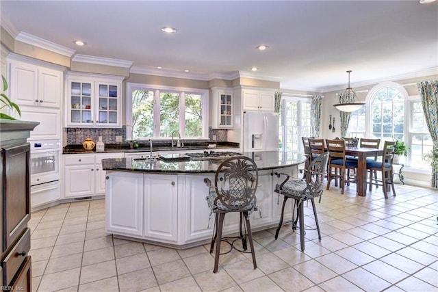 2093 Harpers Ml, Williamsburg, VA 23185 - kitchen featuring white appliances, crown molding, light tile patterned flooring, backsplash, and a breakfast bar