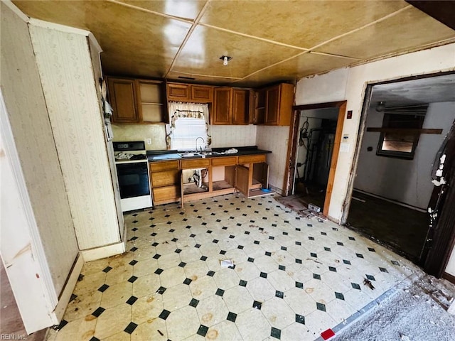 1008 Carrington Ave, Virginia Beach, VA 23464 - kitchen with white range with gas stovetop, dark countertops, light floors, brown cabinets, and wallpapered walls