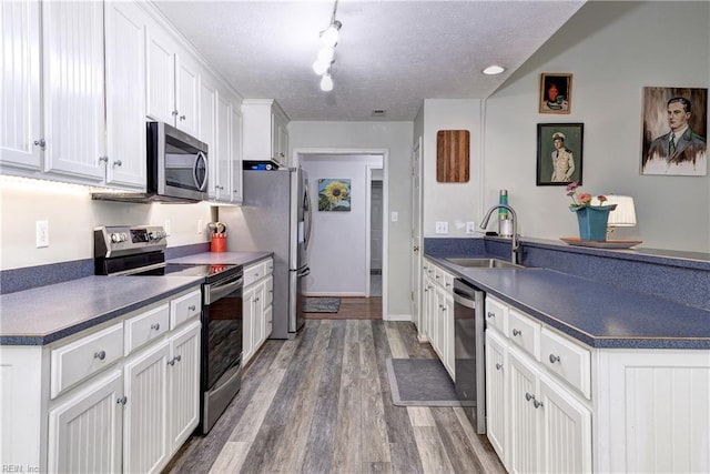 3284 Reades Way, Williamsburg, VA 23185 - kitchen featuring appliances with stainless steel finishes, a peninsula, dark countertops, white cabinets, and wood finished floors