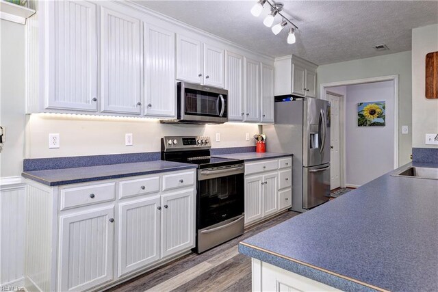 3284 Reades Way, Williamsburg, VA 23185 - kitchen featuring stainless steel appliances, wood finished floors, dark countertops, and white cabinets