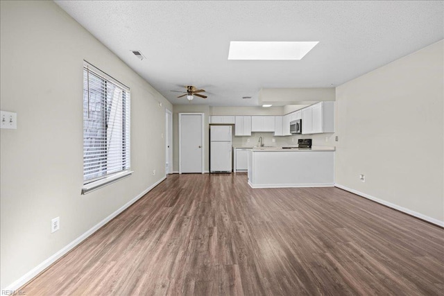1150 Ocean Pebbles Way, Virginia Beach, VA 23451 - unfurnished living room featuring wood finished floors, a skylight, ceiling fan, and a textured ceiling