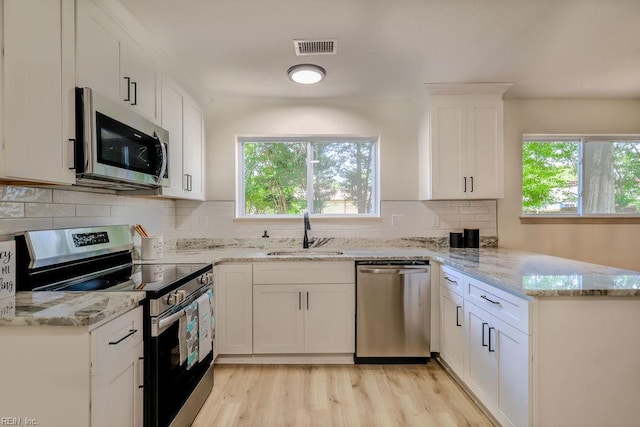 552 Boxwood Ln, Virginia Beach, VA 23452 - kitchen with appliances with stainless steel finishes, a peninsula, healthy amount of natural light, and white cabinetry