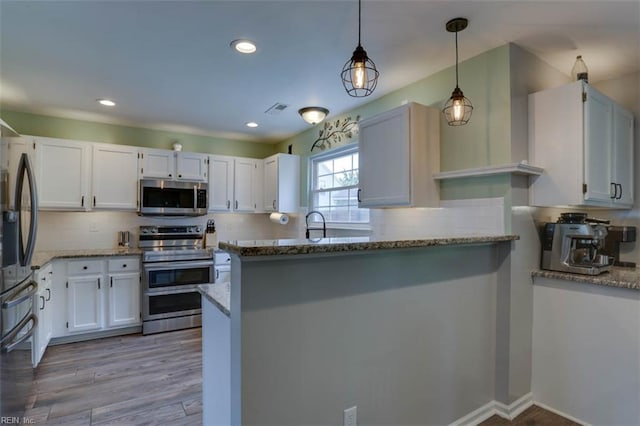 408 Lodge Cv, Chesapeake, VA 23323 - kitchen featuring appliances with stainless steel finishes, light stone countertops, white cabinets, a peninsula, and recessed lighting