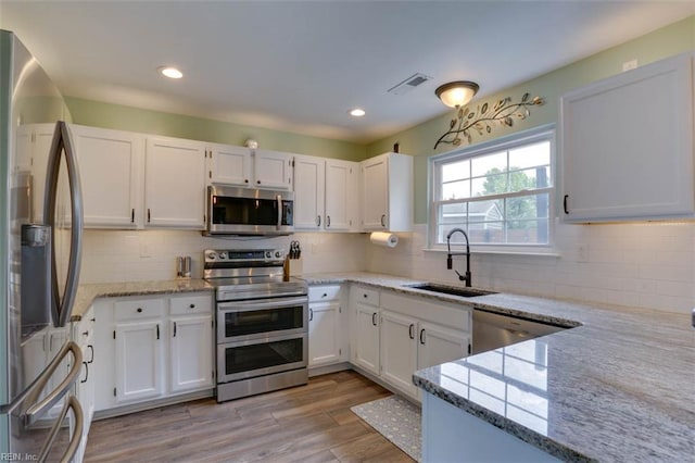 408 Lodge Cv, Chesapeake, VA 23323 - kitchen with appliances with stainless steel finishes, light stone countertops, white cabinets, tasteful backsplash, and recessed lighting