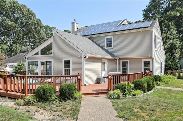 719 Kensington Dr, Newport News, VA 23602 - back of house with a chimney, solar panels, a deck, a lawn, and roof with shingles