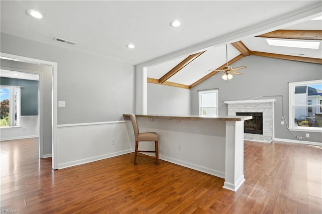 1220 Brahms Dr, Virginia Beach, VA 23454 - unfurnished living room with a skylight, wood finished floors, ceiling fan, a wainscoted wall, and a fireplace with raised hearth