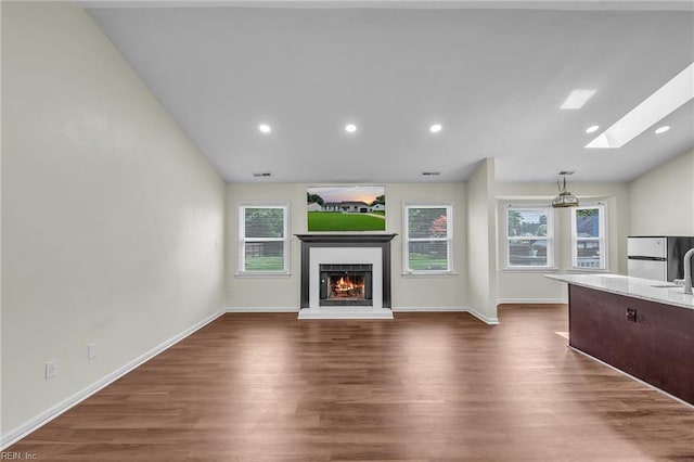 2416 Broadnax Cir, Chesapeake, VA 23323 - unfurnished living room featuring a skylight, dark wood-style floors, a lit fireplace, lofted ceiling, and recessed lighting