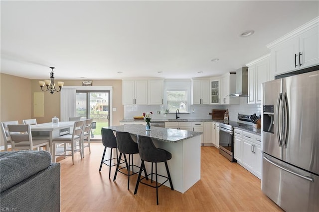 6019 Tabiatha Ln, Lanexa, VA 23089 - kitchen with appliances with stainless steel finishes, wall chimney exhaust hood, tasteful backsplash, a breakfast bar, and light wood-style floors