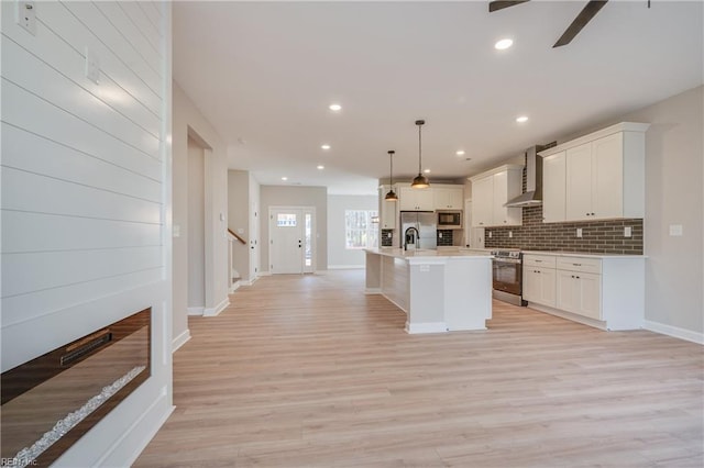 120 Rowland Creek Rd, Moyock, NC 27958 - kitchen with appliances with stainless steel finishes, wall chimney exhaust hood, decorative backsplash, light countertops, and a kitchen island with sink