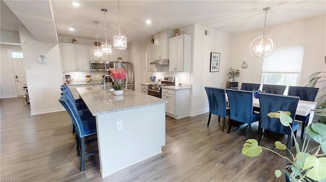 9809 Coral Bells Ct, Toano, VA 23168 - kitchen with stainless steel appliances, a chandelier, wood finished floors, a breakfast bar, and under cabinet range hood