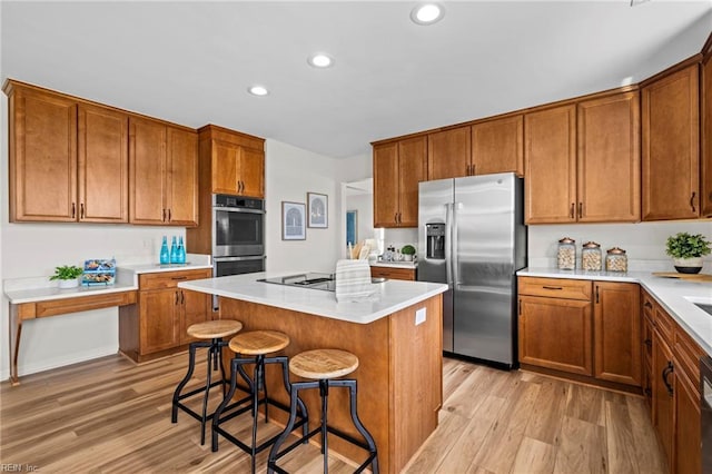 1545 Lake James Dr, Virginia Beach, VA 23464 - kitchen featuring appliances with stainless steel finishes, light wood finished floors, recessed lighting, a breakfast bar, and brown cabinetry