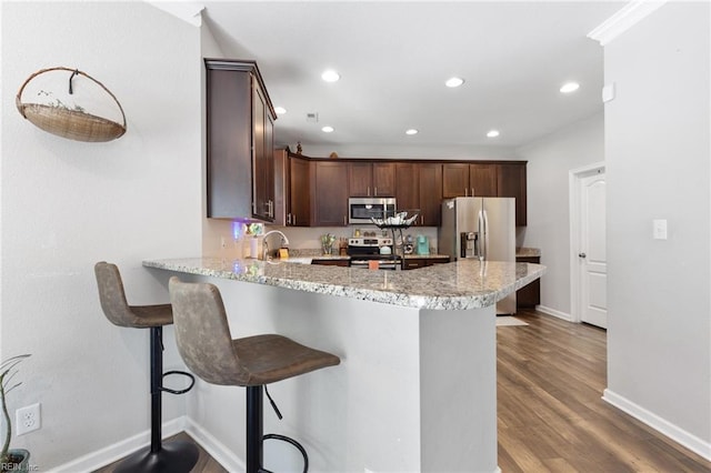 4202 Ravine Gap Dr, Suffolk, VA 23434 - kitchen with stainless steel appliances, a peninsula, dark brown cabinets, wood finished floors, and recessed lighting