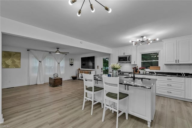 4057 Woodland Dr, Chesapeake, VA 23321 - kitchen featuring stainless steel microwave, a chandelier, dark countertops, a breakfast bar, and light wood-type flooring