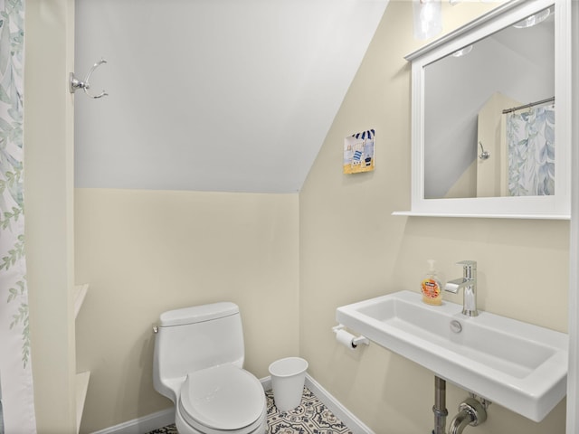 bathroom with lofted ceiling, toilet, curtained shower, and sink