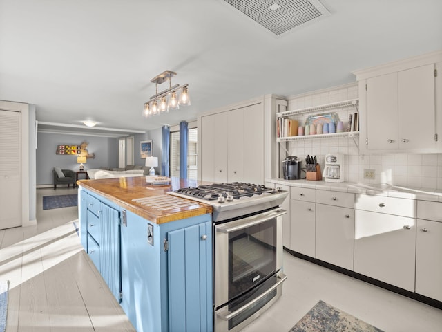 kitchen featuring pendant lighting, butcher block countertops, blue cabinetry, white cabinetry, and gas range