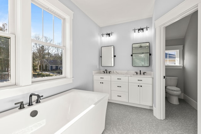 bathroom featuring toilet, a tub to relax in, and vanity